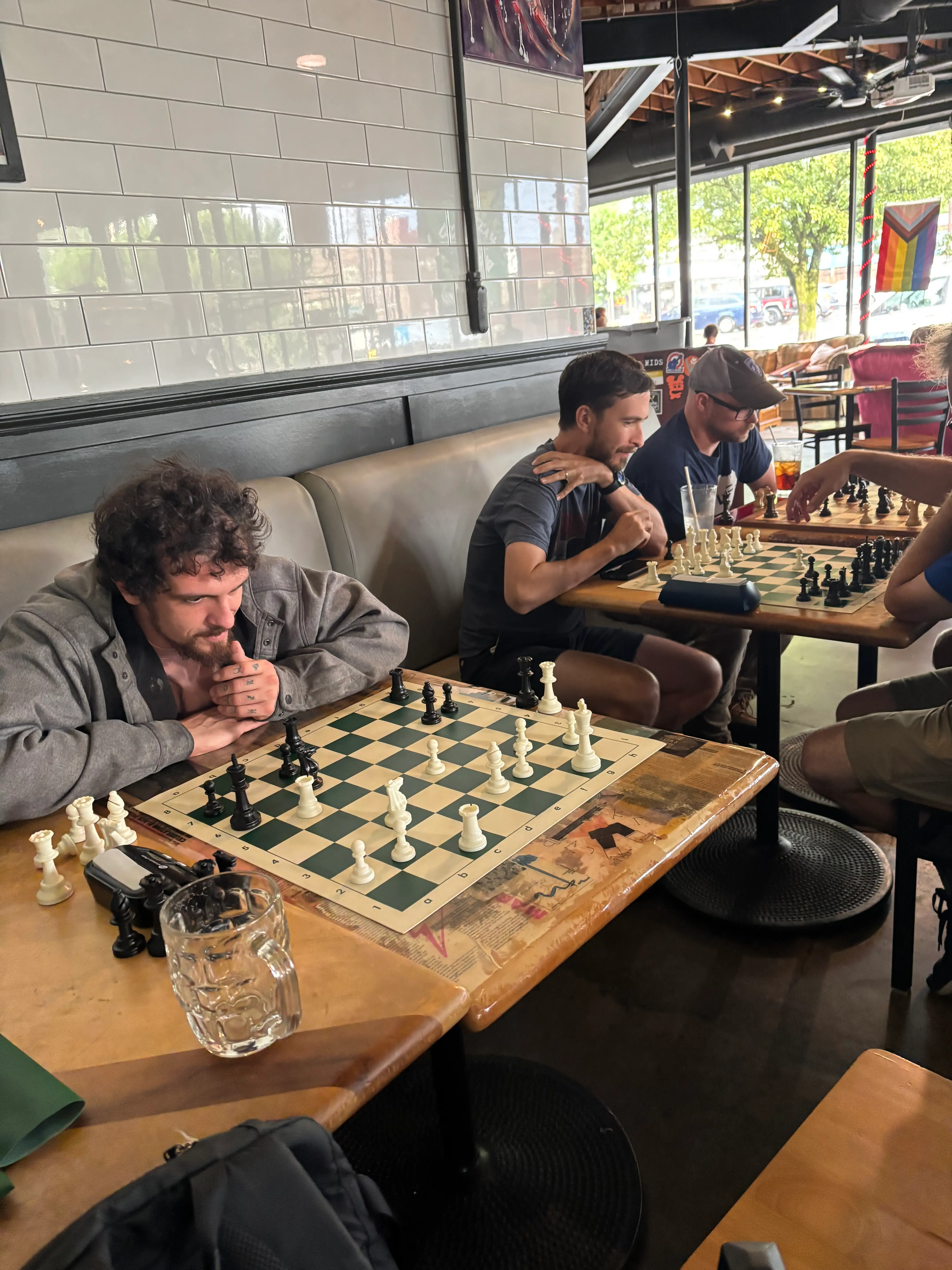 A row of three of chess games in progress at a bar.